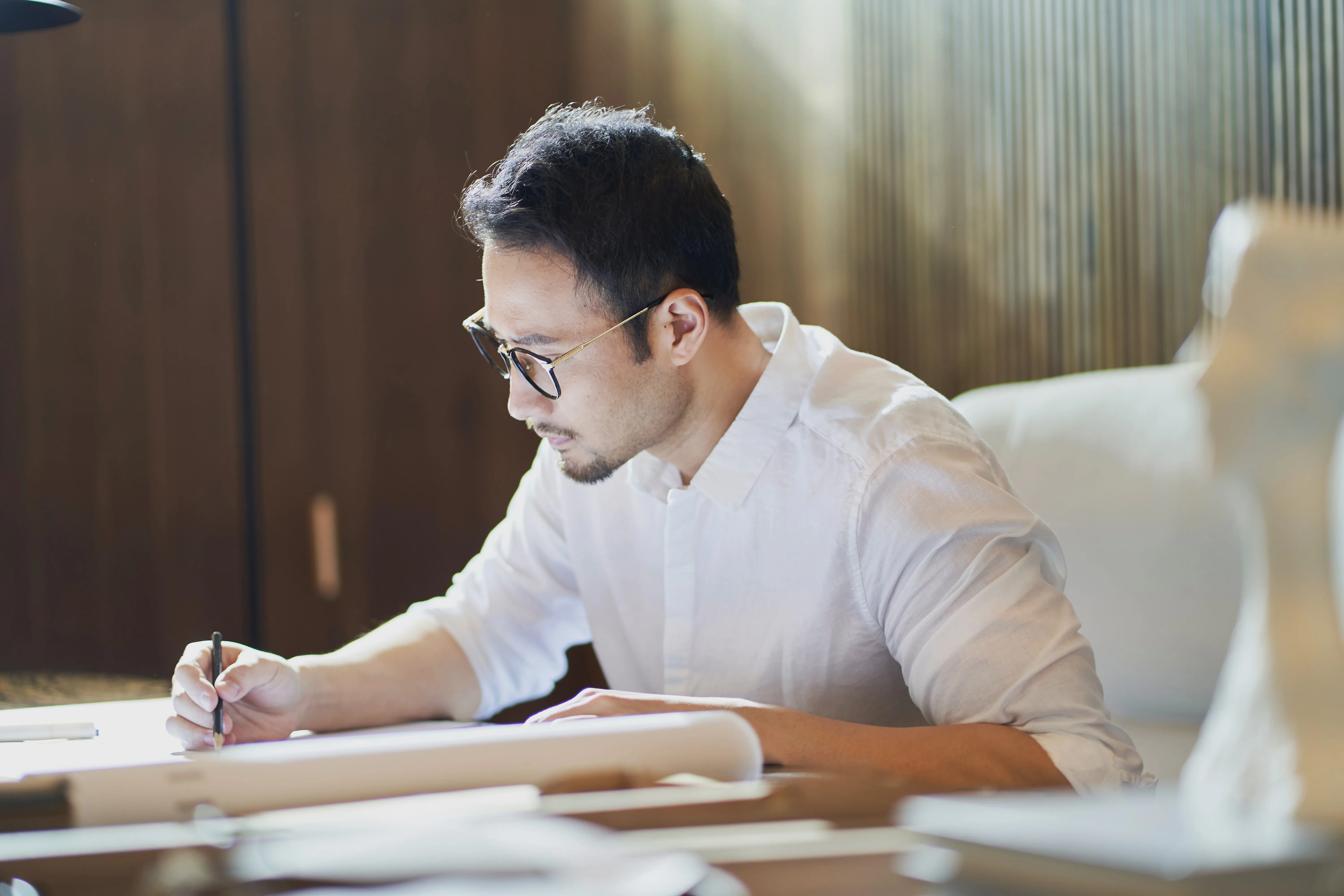 Architect reviewing building plans and design details, an essential step in estimating landed house construction cost in Singapore